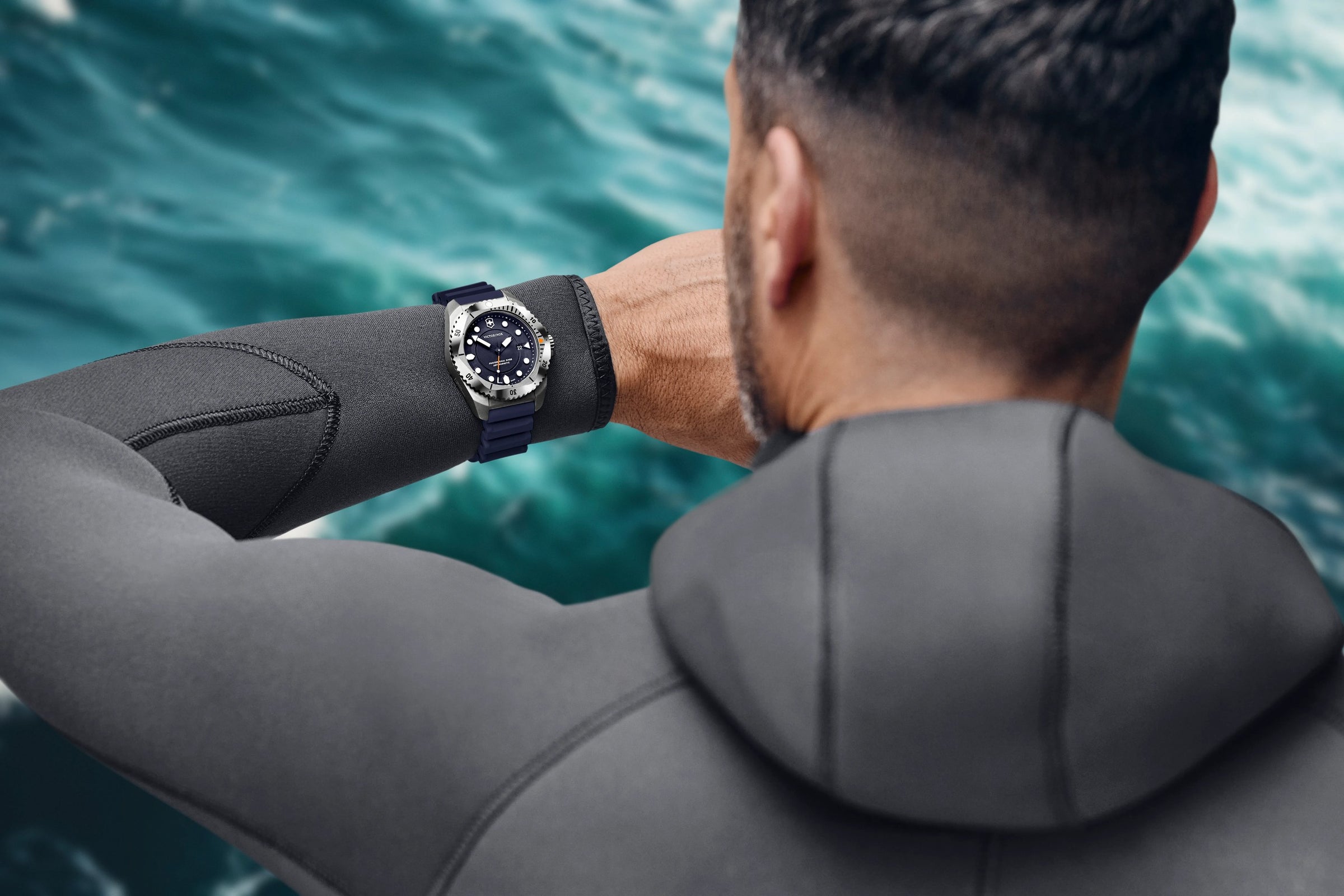 Diver in a wetsuit checking a Victorinox Dive Pro watch over open water